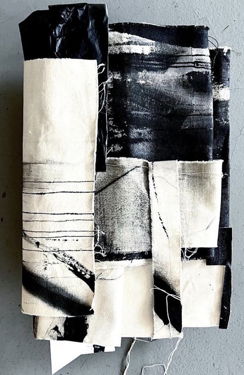 A black and white collage of painted canvas strips, layered and frayed at the edges
